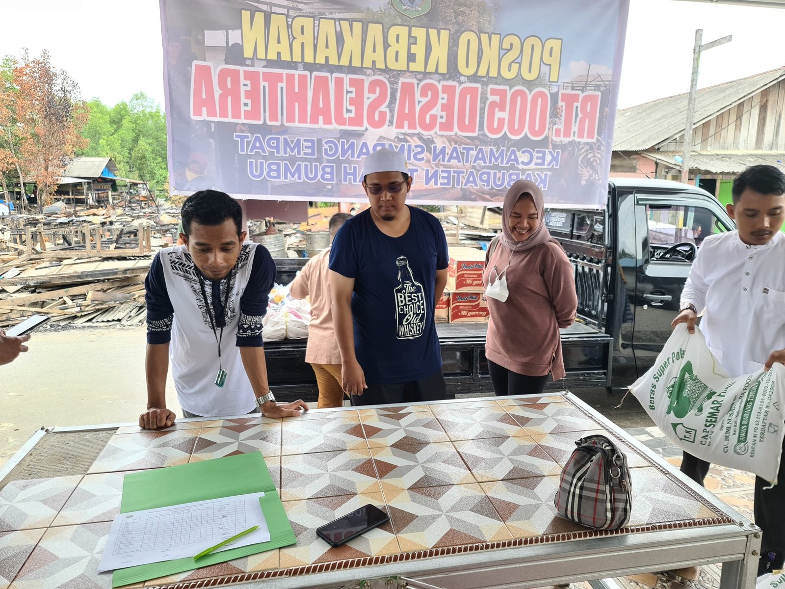 Ketua RT 08 Desa Sejahtera, Rudini, saat menyerahkan bantuan korban kebakaran.