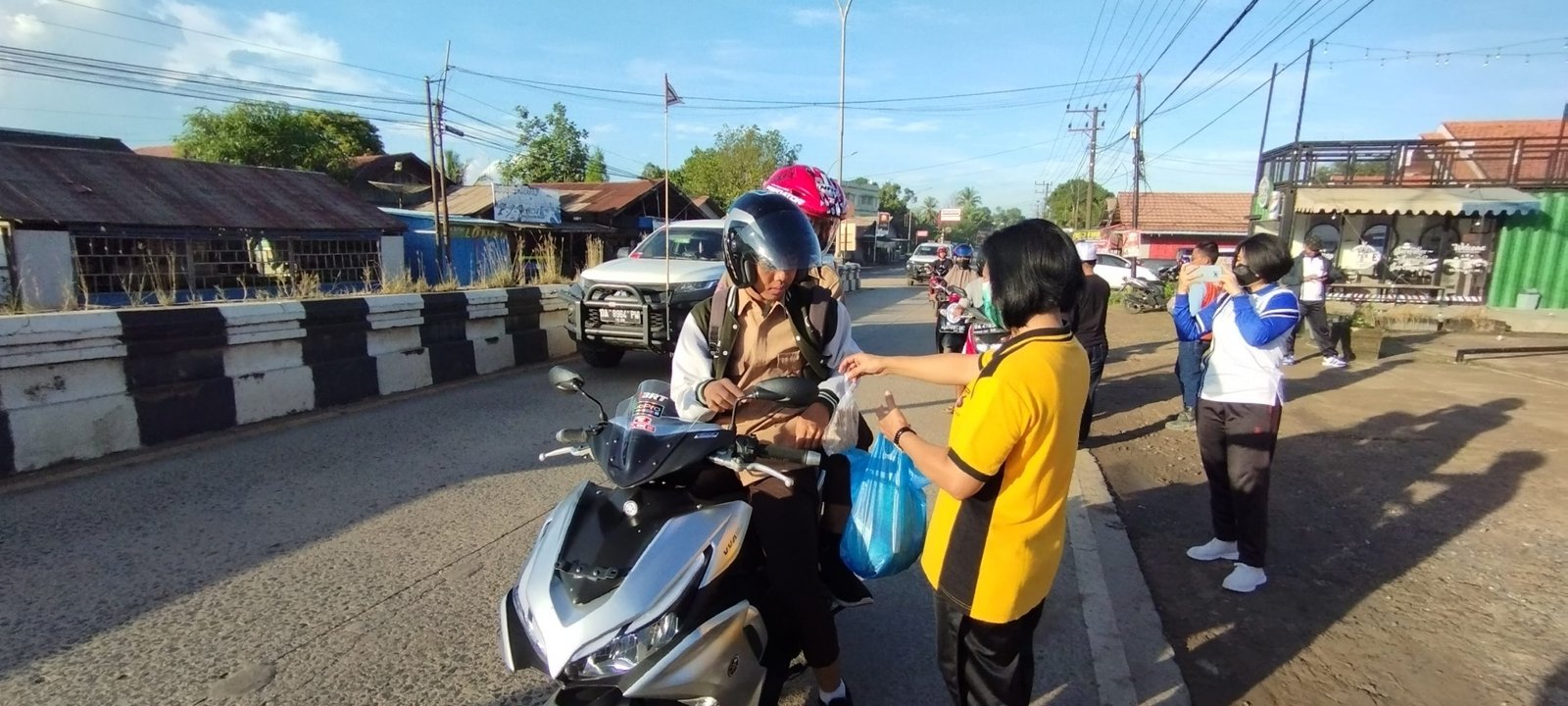 Polwan Polsek Satui saat membagikan nasi bungkus kepada pengguna jalan.